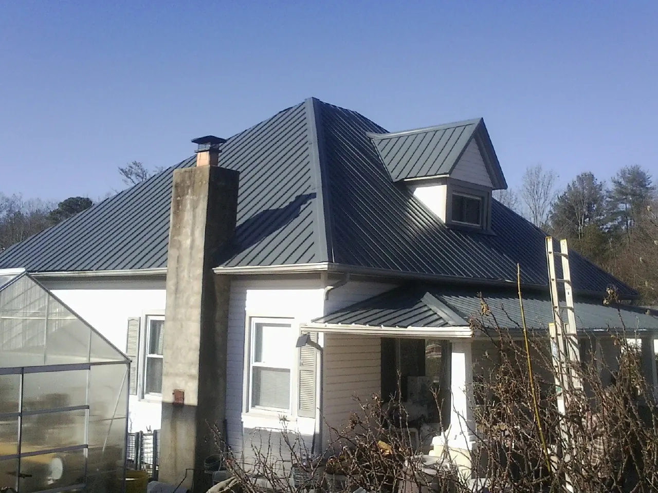 Dark blue standing seam metal roof on a white farmhouse with dormer — Slate & Tile Roof Repair by Roofing Brothers in Lothian