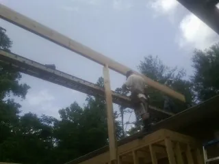 Carpenter setting a ridge beam over a new addition frame — Ice Dam Removal by Roofing Brothers in Lothian