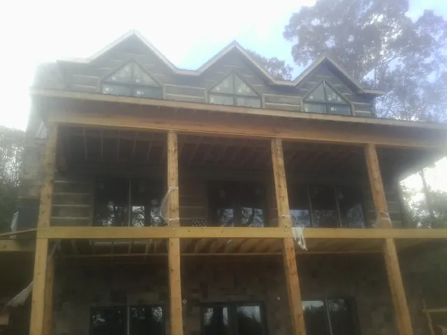 Dormers and porch framing on a large log home under construction — Roof Coating work by our crew in Lothian