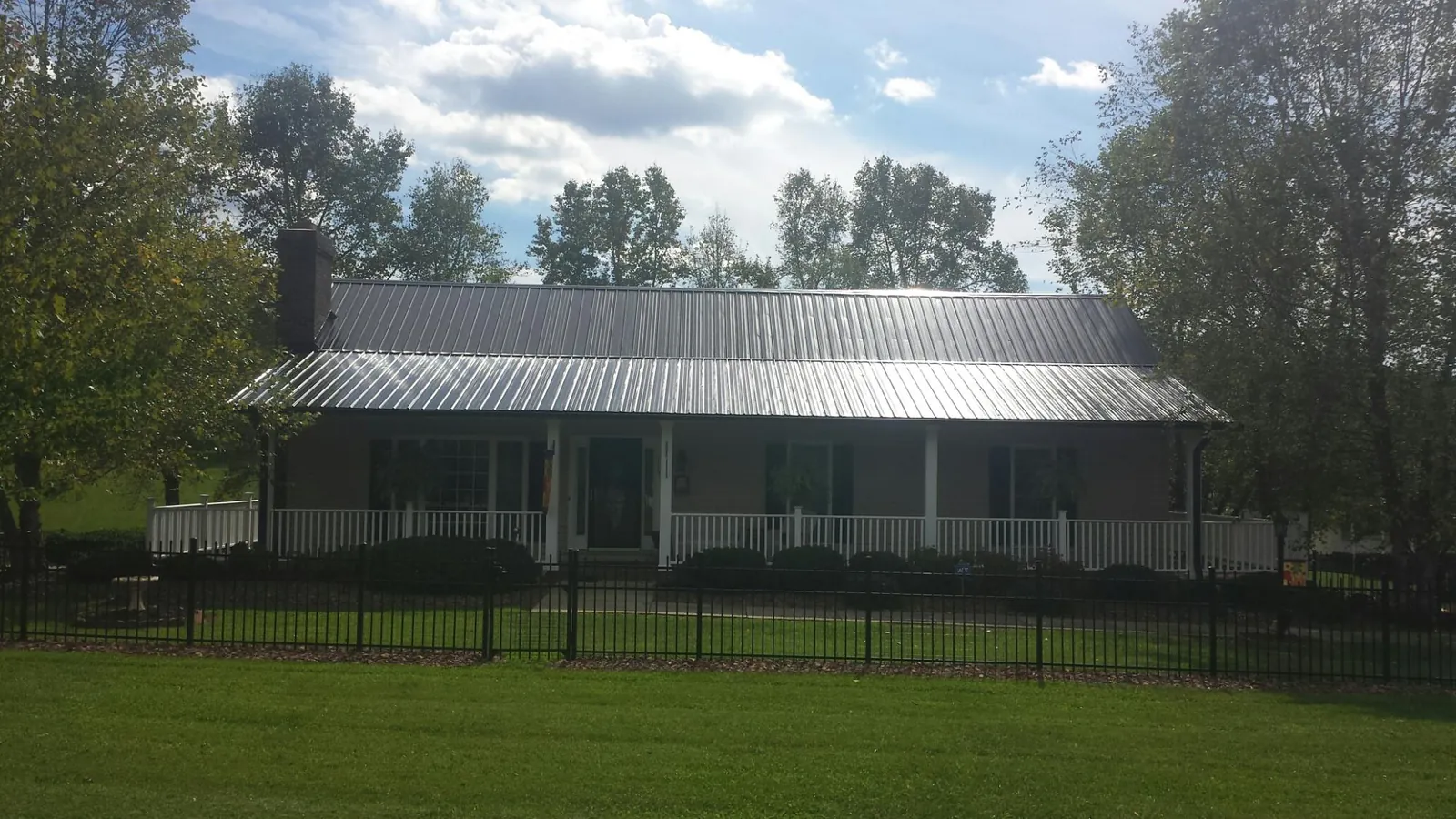 Gray metal roof on a brick ranch with a full width front porch — Gutter Guard Installation work by our crew in Lothian