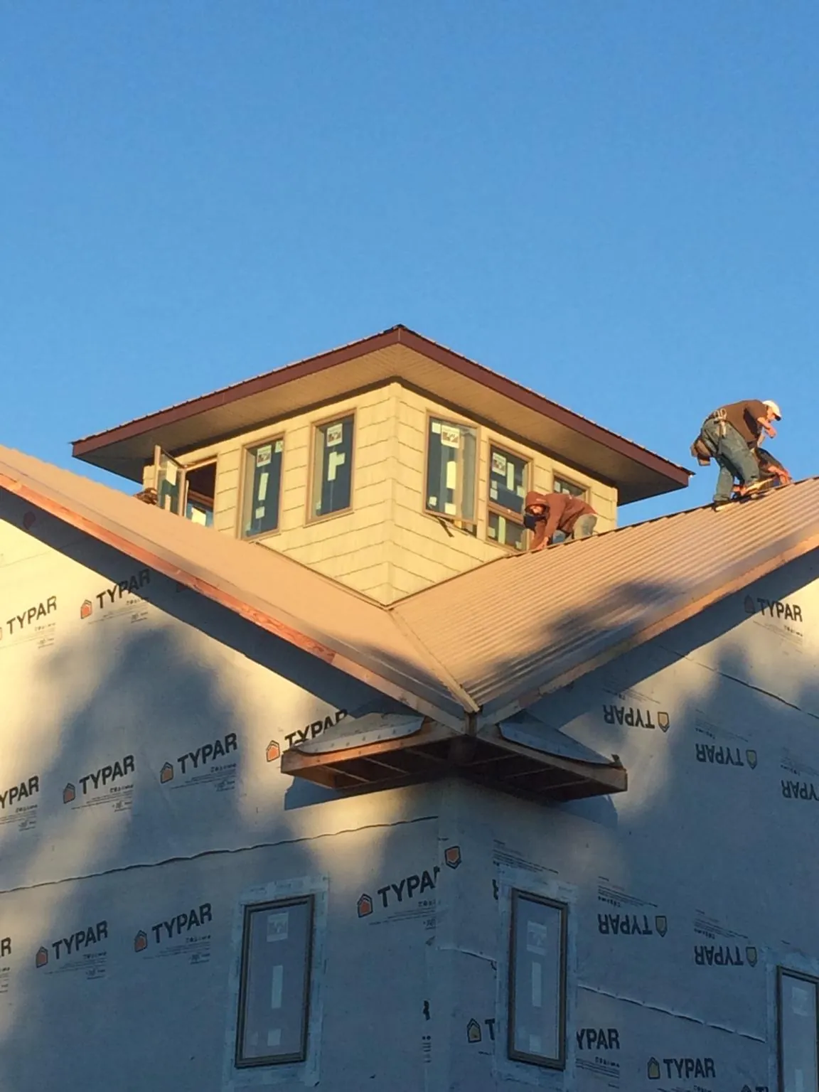 Roofers working around a rooftop cupola on a new metal roof at sunset — Roof Waterproofing in Lothian by Roofing Brothers